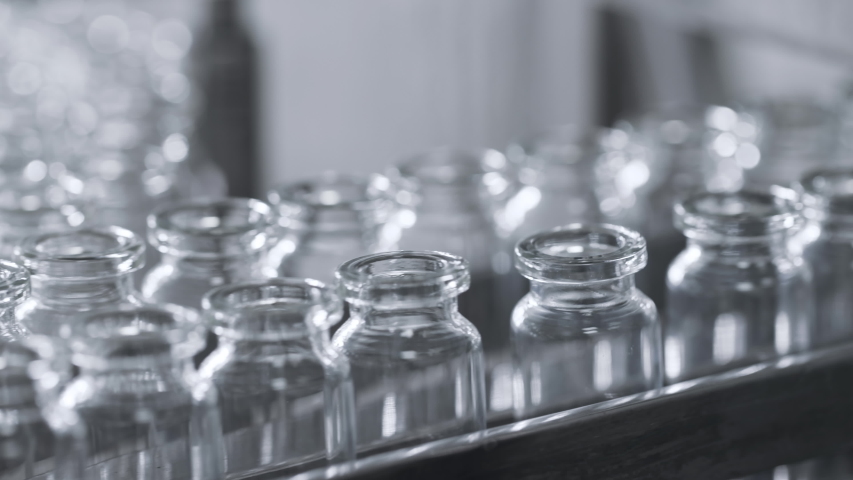 Medical Production of Drugs for Supply of Pharma Industry. Bottle Row on Conveyor Line of Factory. Manufacture Series of Sterile Materials for Pharmaceutical Medication or Cosmetics Mixtures Closeup Royalty-Free Stock Footage #1046960023