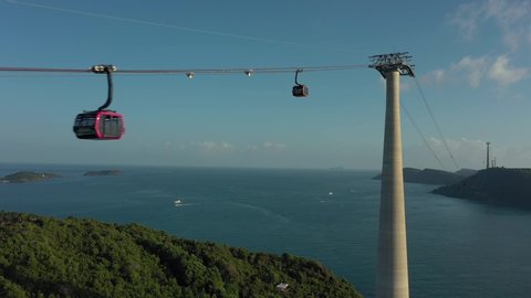 flying through long cable car very close to approaching one another above mountain and ocean water with clear horizon line : vidéo de stock