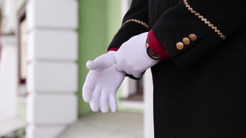 Hotel doorman wearing a suit with white gloves.