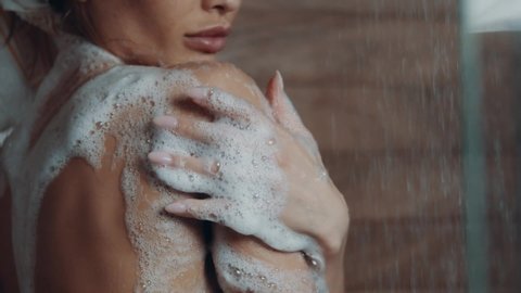 Sexy woman in shower. Attractive young naked girl under water drops. Young beautiful woman taking a shower and washing her body with a shampoo. Beauty and wellbeing concept.