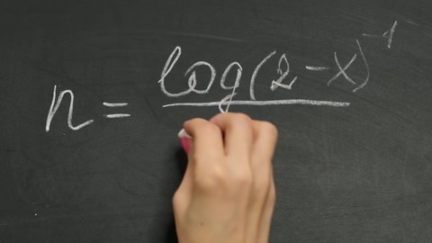 Fhysics teacher writing math formula on chalk board, close up. Mathematics and physics concept.