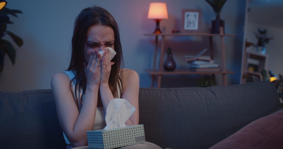 Close up of unhappy woman sitting on sofa using paper tissues, crumpling them and throwing away. Young crying girl with box of handierchief blowing nose and thinking. Emotional breakdown. Royalty-Free Stock Footage #1046976862