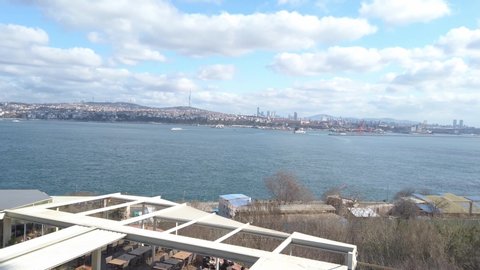 Amazing beautiful view of Bosphorus. Terrace of tourist cafe in Topkapi Palace. White sun umbrellas over tables. Sunny, blue sky, white clouds. Turkey, Istanbul, Fatih, February 2020.