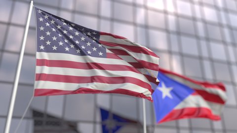 Waving flags of the United States and Puerto Rico in front of a modern skyscraper