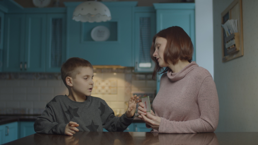 Mother teaching autistic kid with cards at home. Kid with autism learning numbers with mother showing educational cards on the kitchen.  Royalty-Free Stock Footage #1046991475