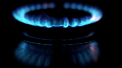 Gas is switching on, apearing blue flame. Gas stove on black background. Slowmo