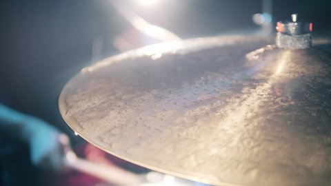 A musician plays drums, hitting wet cymbal.