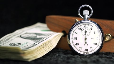 The stopwatch lies next to the money in a nine-pin clothespin. A stack of dollars in a clip.