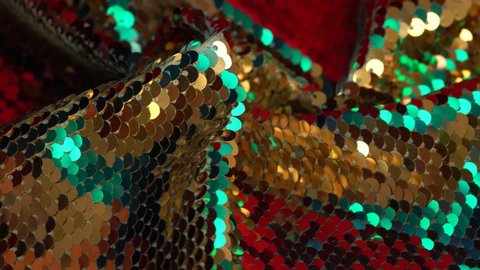 Fabric sequins red, gold and mint colors. Holiday abstract glitter background with blinking lights. Fashion luxury fabric glitter, spangles, paillettes