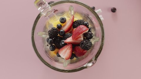 Top view fresh berries, strawberries, blackberries and blueberries fall in blender to make smoothie. Slow motion video