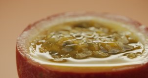 Macro shot of sliced fresh exotic passion fruit with pulp spinning on table. Slow motion video