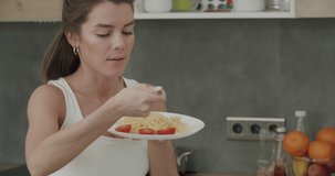 Italian food. Close-up of healthy caucasian woman eating spaghetti with tomatos. Perry girl in home clothes having fun with vegeterian pasta. 4k raw footage slow motion