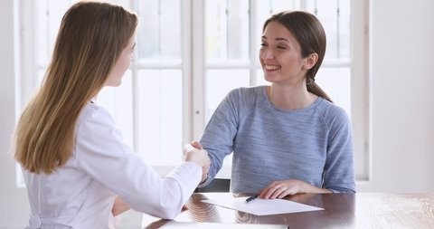 Young adult woman patient put written signature on medical form giving consent agree on medical services concept handshake female doctor during healthcare consultation.