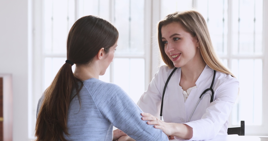 Smiling kind female professional medic doctor encouraging young adult woman patient giving care and support concept helping reassuring client having trust conversation at medical consultation meeting | Shutterstock HD Video #1047021439