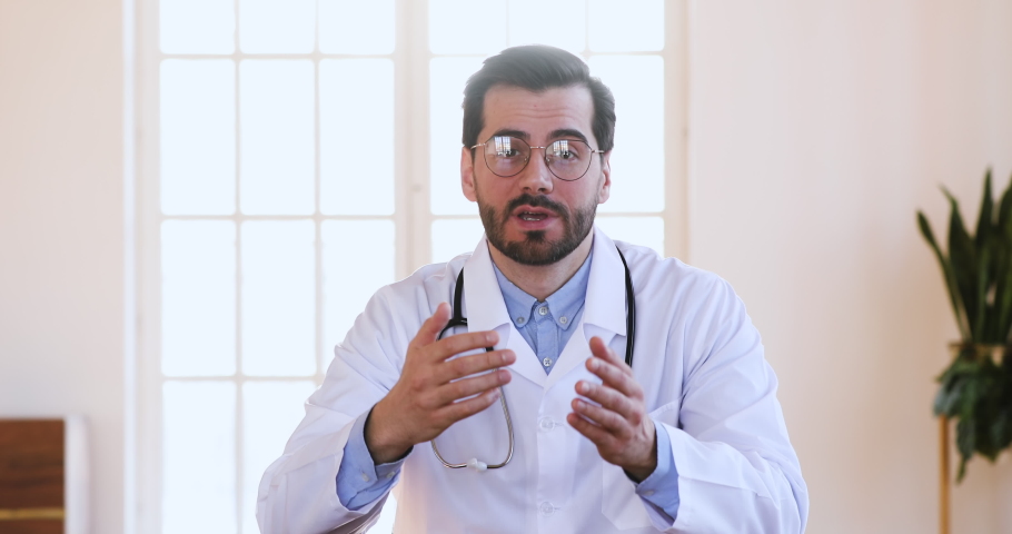 Professional male doctor physician in white medical uniform speaking looking at camera make video chat conference call or recording healthcare webinar training talk to distant patient, webcam view | Shutterstock HD Video #1047021463