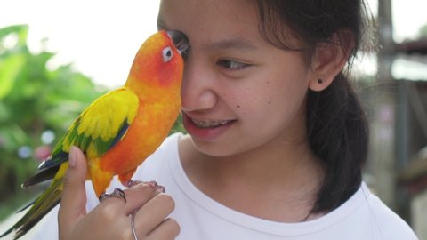 Close-up portrait of a asian girl playing with bird in joyful, slow motion.