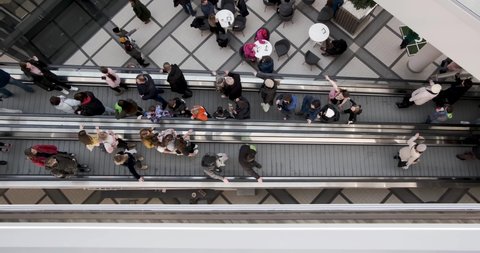 crowd of people on an escalator in a large multi-storey layered shopping center. view from above