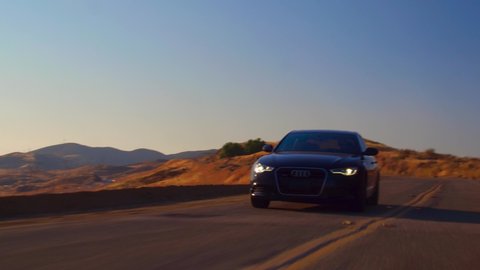 Los Angeles, California / USA 02 5 2010 Black Car Audi A6 with driving on mountains road during sunset and mountains in background low light shot. 