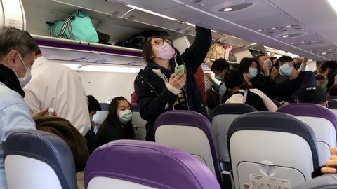 Taipei, Taiwan-05 February, 2020: 4k Interior airplane, male and female passengers wearing surgical mask to prevent infection from coronavirus. People with masks take luggages for get off airplane-Dan
