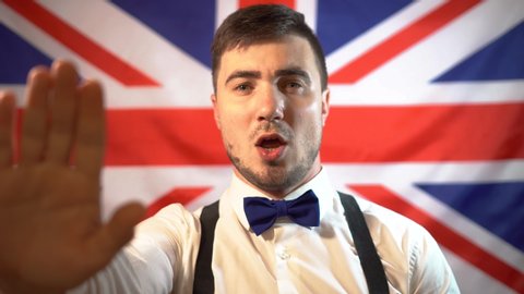 A British patriot, a British politician, takes the oath against the background of the flag of Great Britain and sings a hymn, holding out his hand. British politician takes an oath, sings a hymn