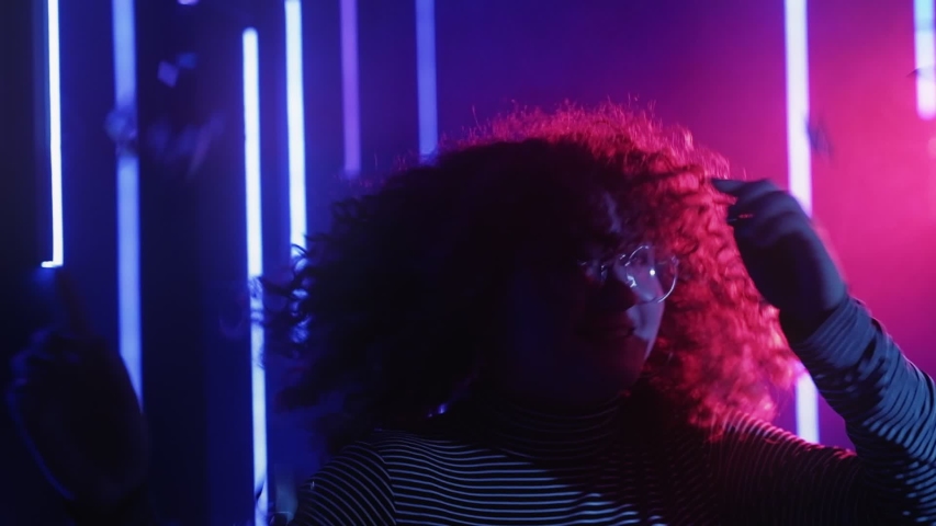 Neon girl. Birthday celebration. Excited young woman dancing in blue pink glow confetti rain.