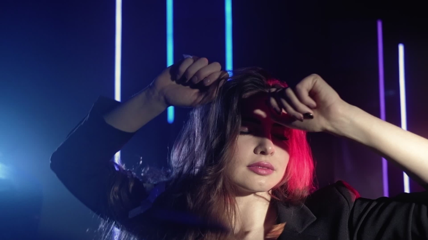 Neon light girl. Party night. Woman with closed eyes enjoying dancing in confetti rain.