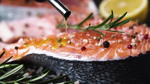 Chef pours salmon steaks with olive oil, slow motion. Healthy eating concept.