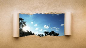 Creative 4k time laps video of fast moving clouds in the blue sky at sunset witn sunflare that are visible through a hole with torn edges in old retro grunge vintage paper.