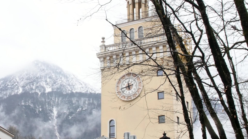 Church chapel with a clock on the wall of its tower with a snowy mountain peak on the background. Stock footage. The architecture of old european town.