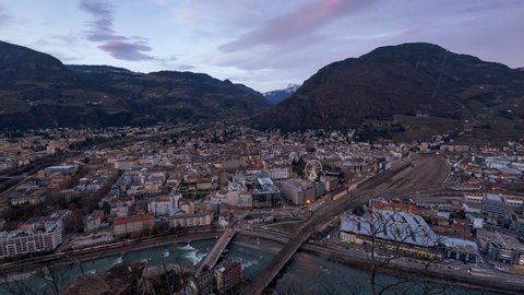 Bolzano, Bozen aerial cityscape - the transition from day to night video. Time lapse from viewpoint. Ferris wheel and lots of traffic, with station area