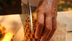 video cutting ripe pineapple with a knife on a table in sri lanka