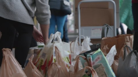 Volunteers fill grocery bags full of food  donations, as they do a good deed for the needy, elderly, and less fortunate by donating their time and food. Hands, shallow depth