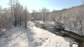 Beautiful river amid snow-covered Winter wonderland landscape, aerial drone view.
