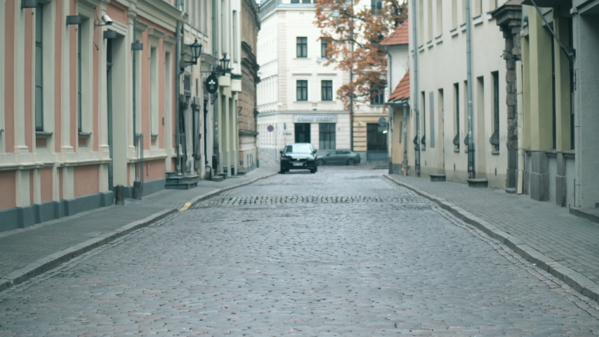 A woman walks along the a street in historical part of a city.