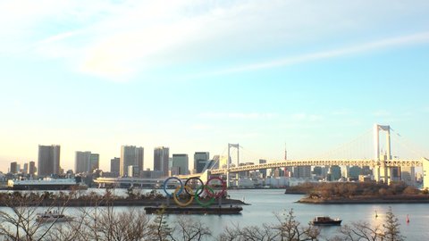 TOKYO, JAPAN - FEB 2020 : The five ring symbol of the Olympic Games in front of Odaiba Rainbow Bridge. Japan will host the Tokyo 2020 summer Olympic and Paralympic. Shot in sunset time.