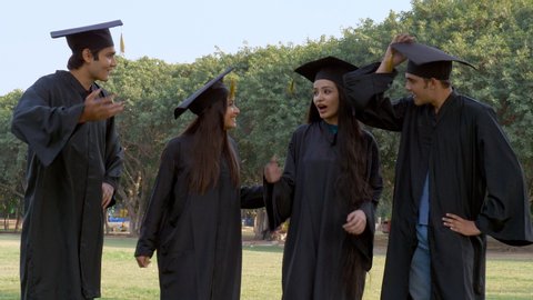 Young happy graduates throwing their graduation hats in the air - celebration time. Group of excited Indian students tossed their academic hats into the air while celebrating their graduation day -...