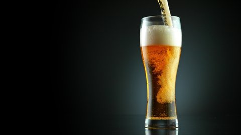Super Slow Motion Shot of Pouring Fresh Beer into Glass on Black Background at 1000fps.