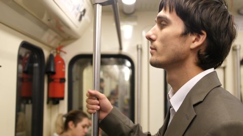 Young handsome businessman in suit standing in the subway on the way home from work