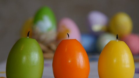 Candles made in shape of easter egg. Candles extinguished from the air.. Green, orange, yellow. Easter eggs candles and colorful Easter eggs in the background.