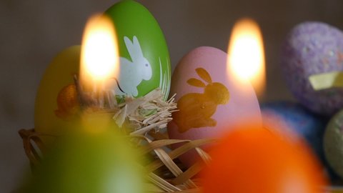 Candles made in shape of easter egg. Green, orange, yellow. Easter eggs candles and colorful Easter eggs in the background. Focus and refocusing.
