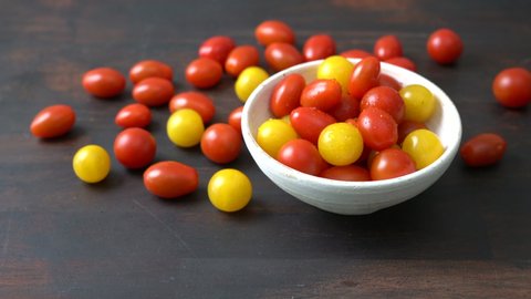 Small tomatoes in a cup and on a dark  table. The camera approaches from the front from above