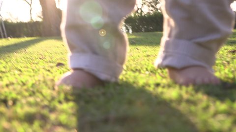 Baby feet toes feeling grass in outdoor nature during sunset
