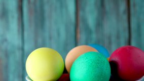 Colorful easter eggs in a basket revolve on a wooden background. Easter concept background.