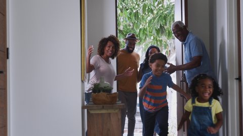 Grandparents at home opening door to visiting family with children - shot in slow motion
