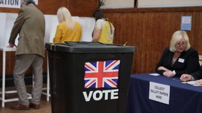 4K: Voter inserts ballot paper into box at a Polling Station - They are voting in the United Kingdom with the UK flag. Stock Video Clip Footage