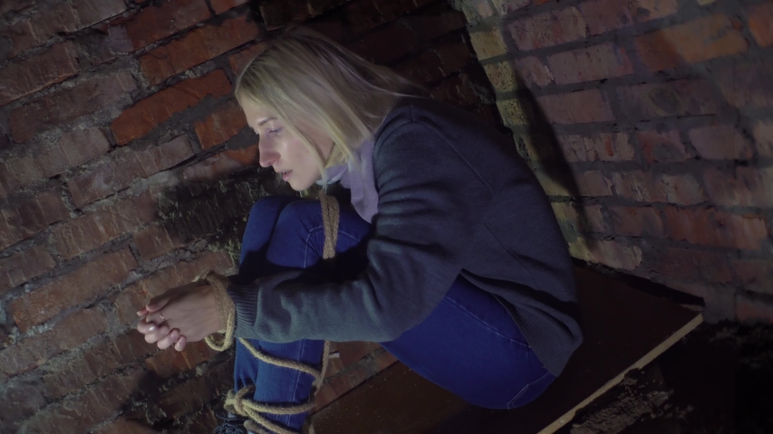 woman trying to free her hands from the rope.  