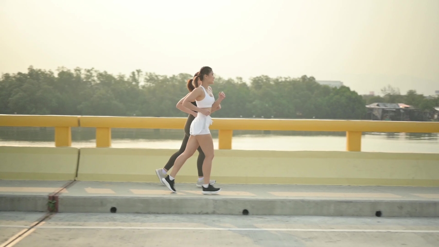 Slow motion athlete woman running at the beach road. Asian female runner endurance training in summer. Healthy lifestyle and sport