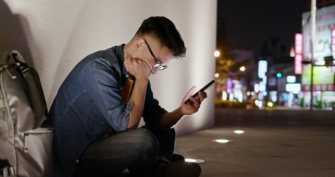 asian man is upset while using smart phone outdoor in the evening