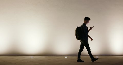 silhouette of asian young man use smart phone outdoor in the evening