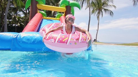 slow motion of asian girl playing on an inflatable slide in aquapark